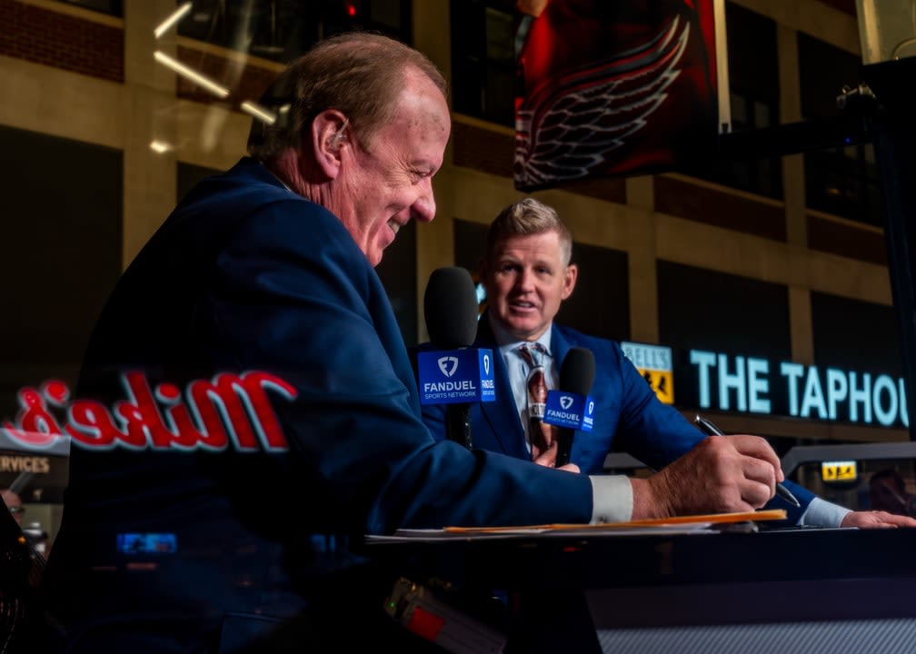 John Keating in forefront and Chris Osgood at a broadcast desk holding microphones