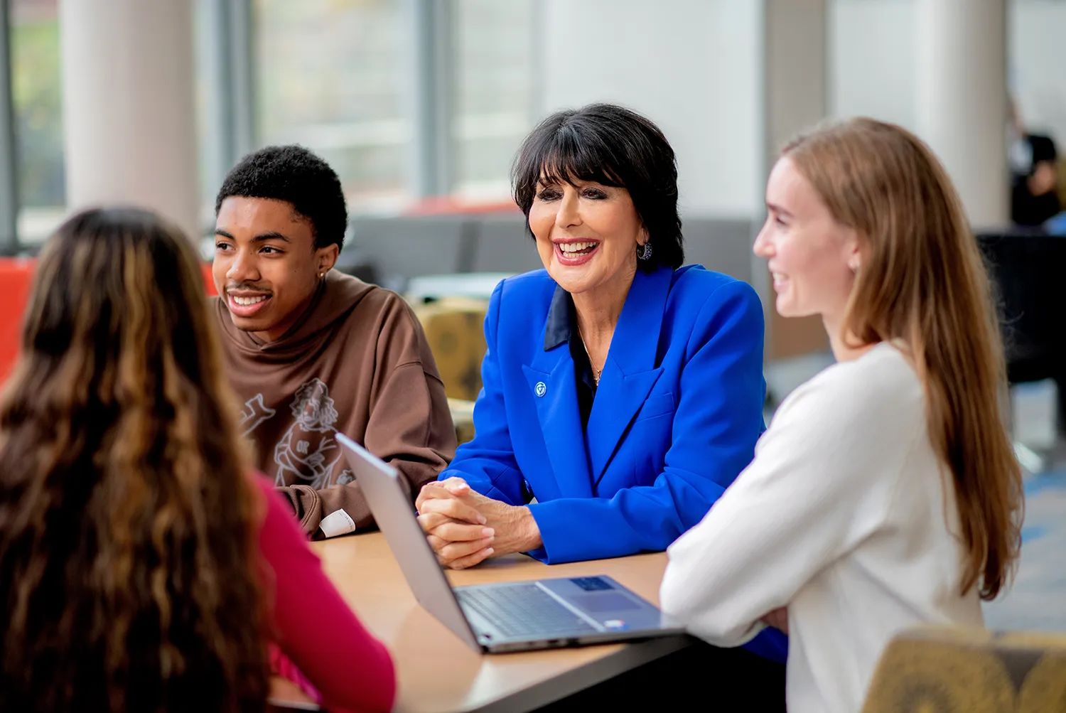 Philomena Mantella, President, seated with students around a table