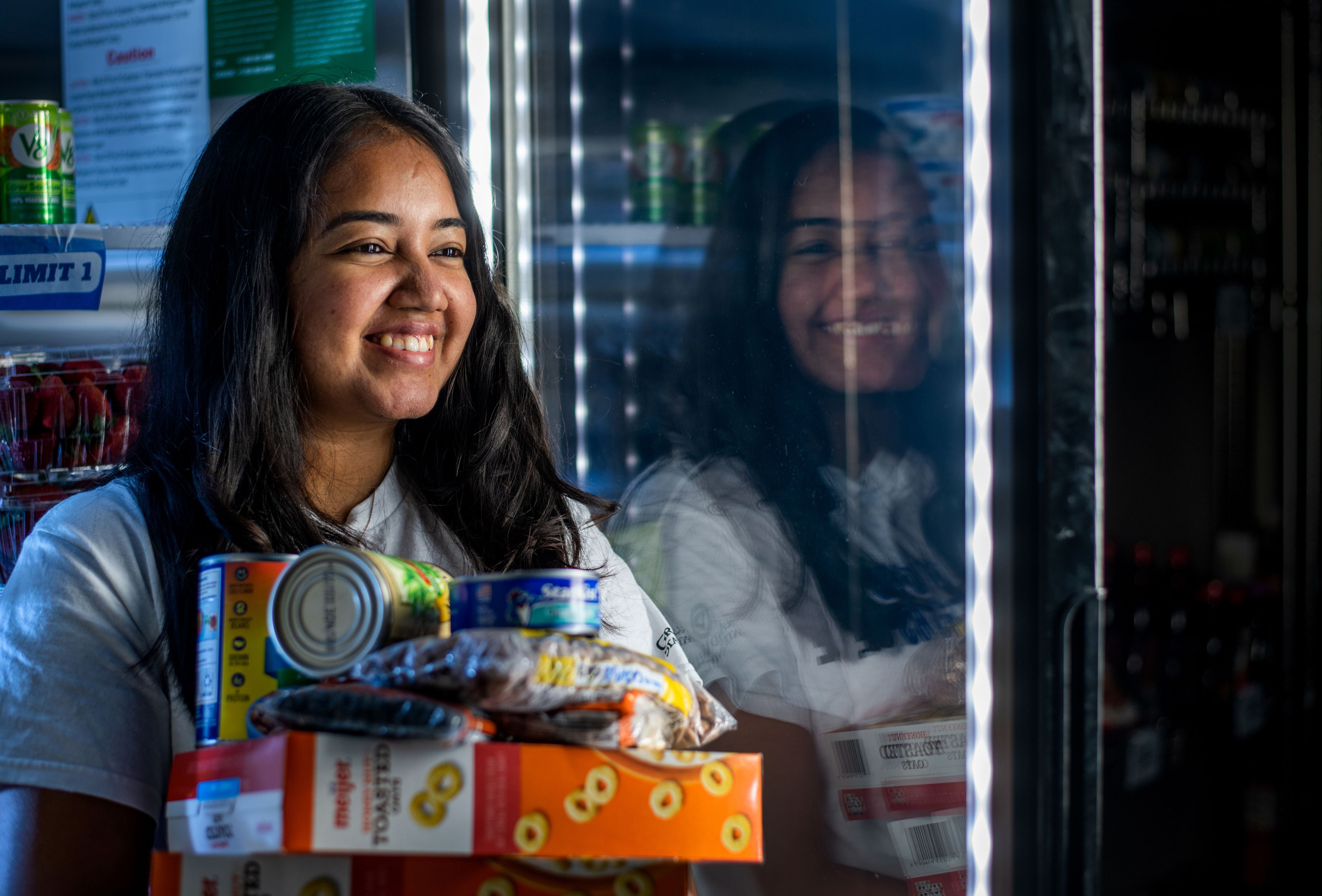 student holding variety of groceries in arms next to cooler