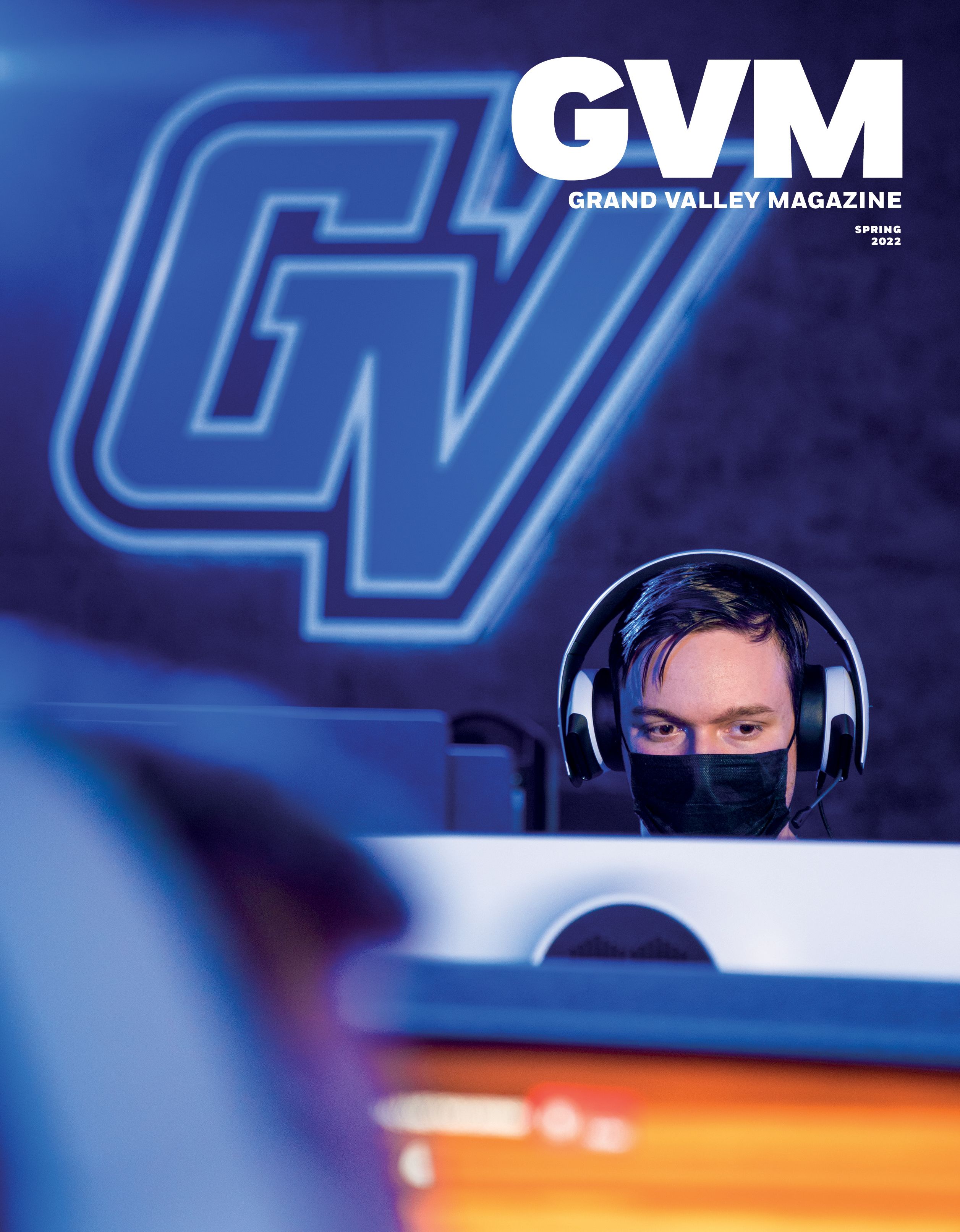 a boy in a mask playing a computer game in the GVSU E-Sports room,
