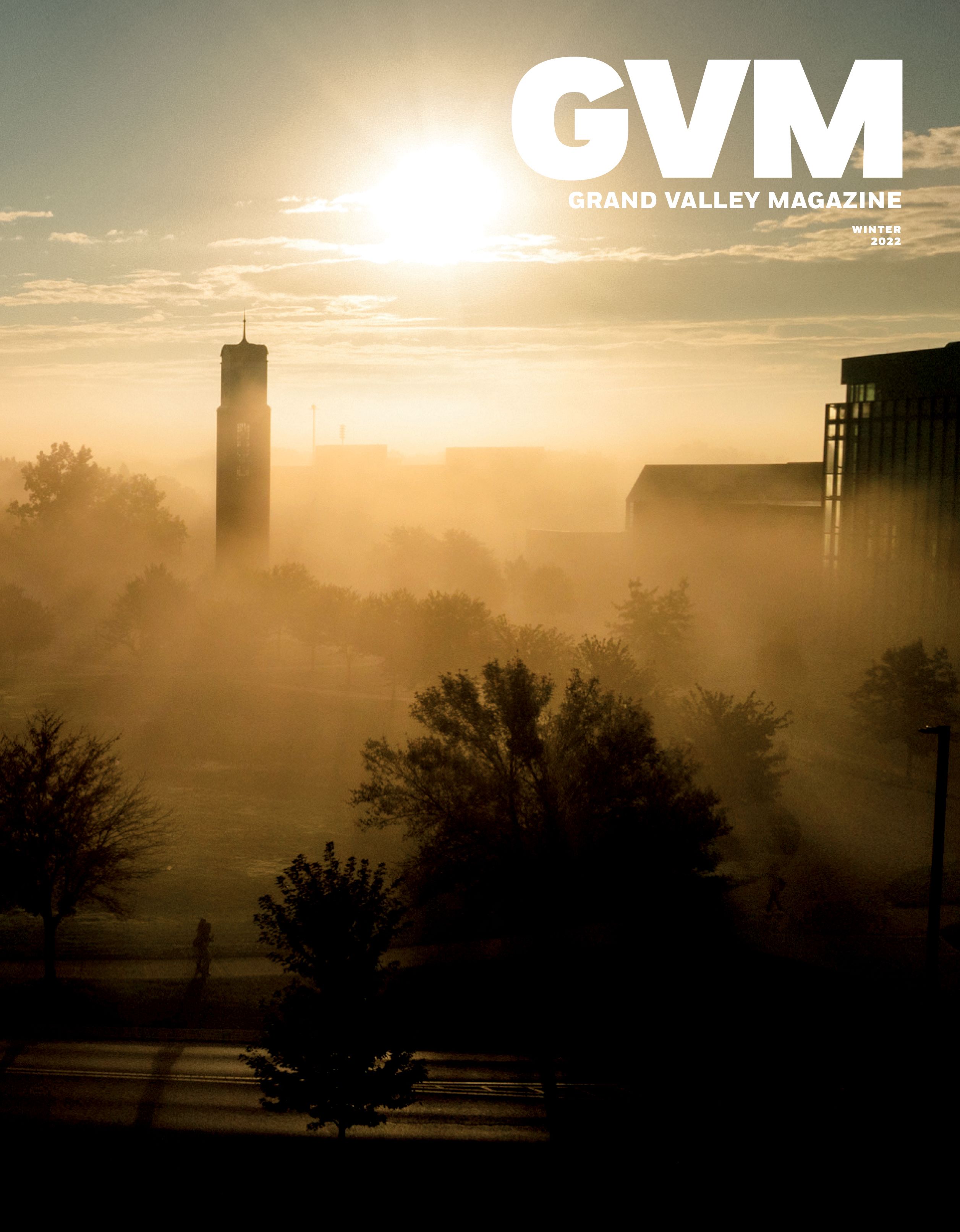 a foggy morning looking at the clock tower on the left and the library on the right from a-far with the sun in the background
