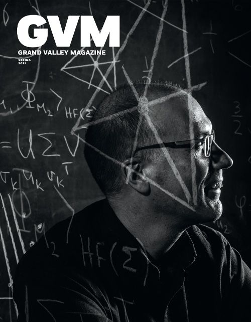 A man looks off to the right of the frame, math symbols are written in chalk on a blackboard behind him, and overlayed on his face. Image is in a dramatic grayscale tone.