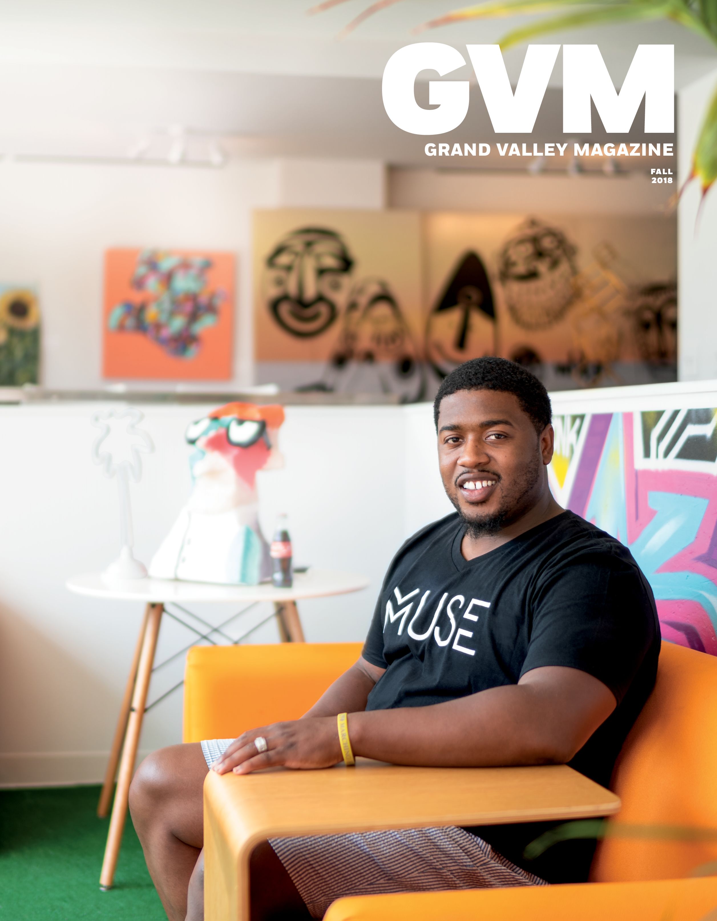 a photo of stephen smith sitting on a orange couch in a white room. 