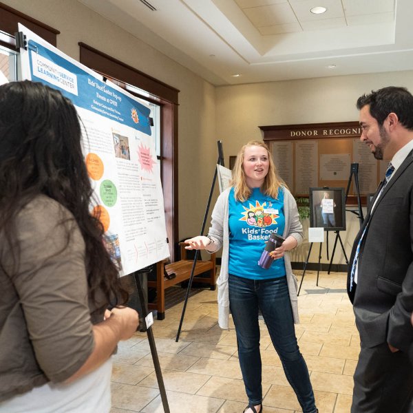 At right, Travus Burton, director for Civic Learning and Community Engagement, looks at a poster presentation from the 2019 Civic Engagement Showcase.