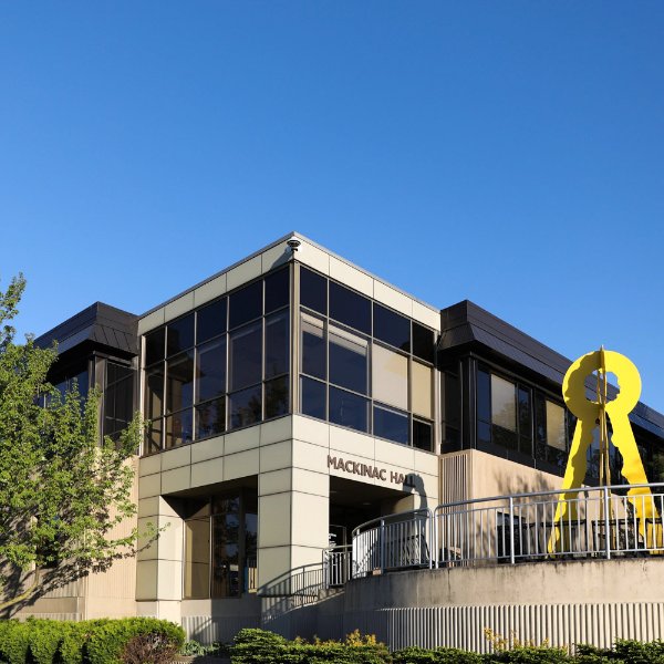 The entrance to a building with the words Mackinac Hall over the entrance. A yellow art sculpture is near the entrance.