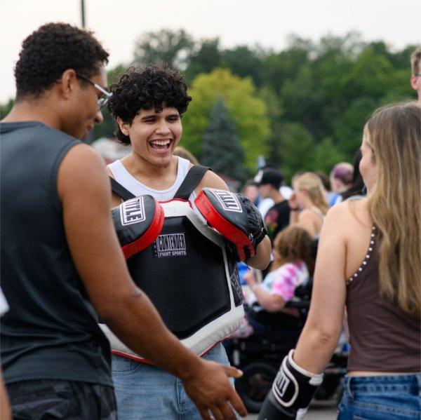 Gustavo Alonzo, a member of the GVSU Boxing Club, laughs while encouraging a student to try out punching gloves during Campus Life Night.
