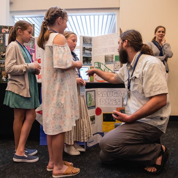 A teacher talks with students about a science project.