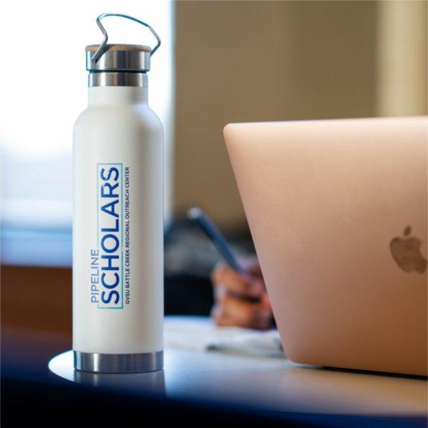 water bottle, Battle Creek Pipeline Scholars, GVSU, sits next to a MacAir laptop