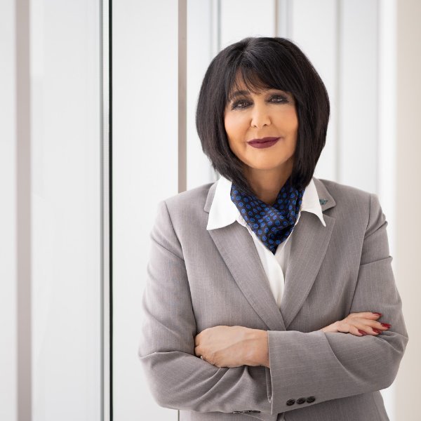 President Philomena V. Mantella standing for portrait in grey suit with blue scarf