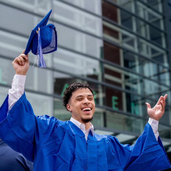 A Grand Valley grad spreads his arms in triumph in front of Van Andel Arena.