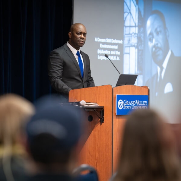 man at podium, with presentation screens showing Dr. King