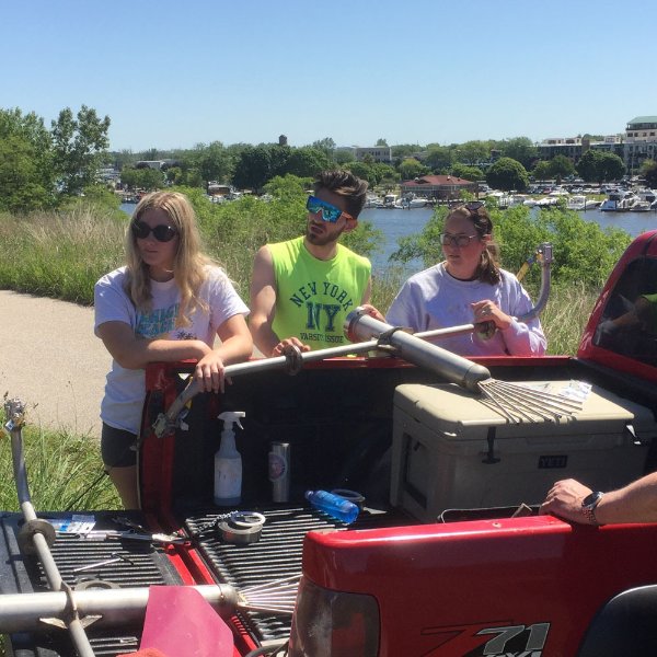students unload supplies from a pick up truck, a river appears behind them
