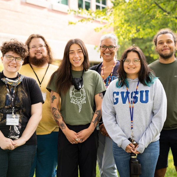 six people standing in two rows outside on the Allendale Campus