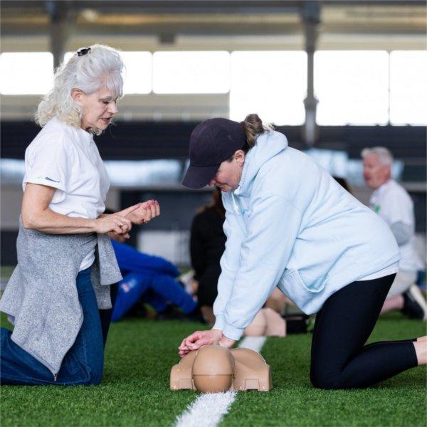 Debra Yake (left), an instructor with Champions of the Heart, guides Bonnie Vankampen (right) through proper chest compression technique during a CPR training session at the Kelly Family Sports Center on Grand Valley State University�s Allendale campus on April 12, 2026. Participants practiced hands-only CPR in rhythm to music to maintain effective compression timing.