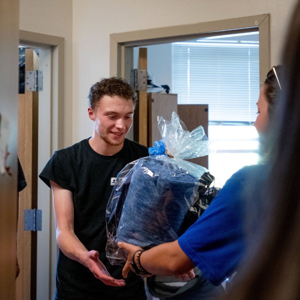Connor Pung holds a gift basket being presented to him during his move-in.
