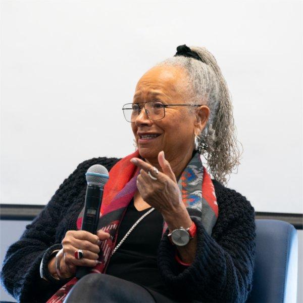 Ann Smith holds a microphone while seated in a chair