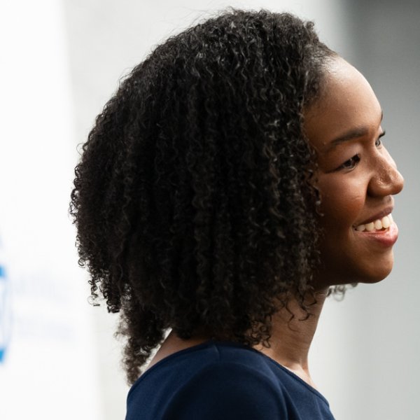 Krya Harris Bolden smiles against a photo backdrop with the GVSU word mark printed on it