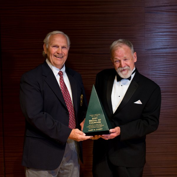 From left, James Scott hands Gary Chopp the Medal of Courage during the induction ceremony at the National Wrestling Hall of Fame; both men are standing