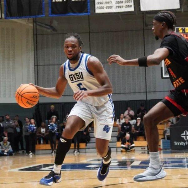 A Lakers men's basketball player drives toward the basket with an opponent guarding him.