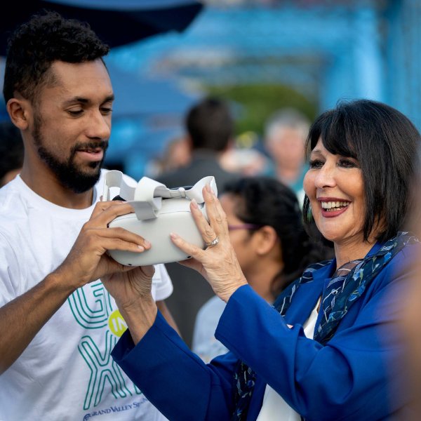 One person hands another a VR headset.