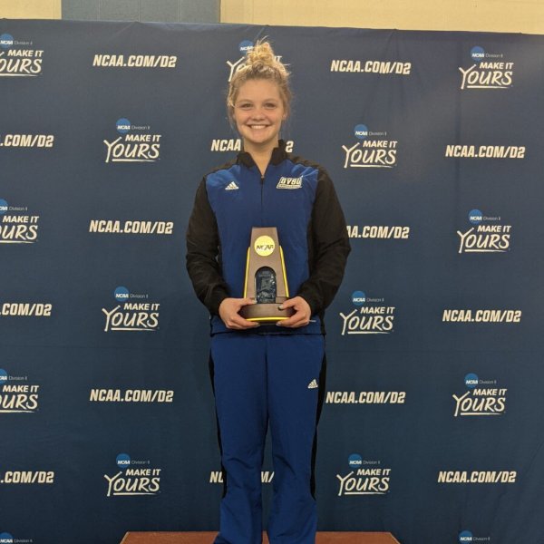 Gracyn Segard stands with a national championship trophy on a podium.