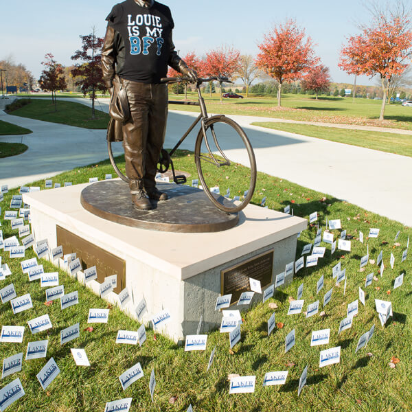 statue of Bill Seidman surrounded by small Grand Valley flags