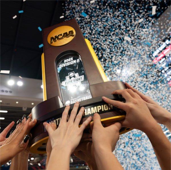 Members of the GVSU women's basketball team lift the national championship trophy.