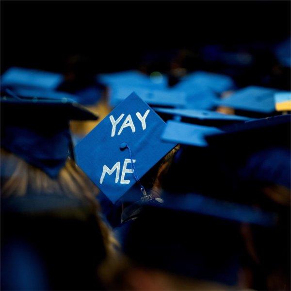 A person wears a graduation cap with the words, "Yay me."