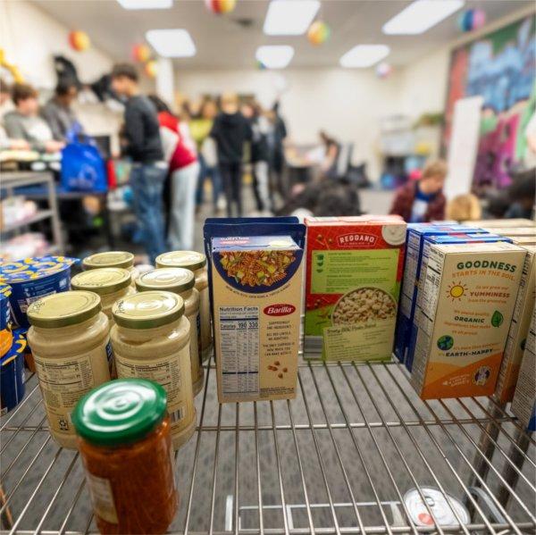 a food shelf in Replenish, with students in background helping to sort items