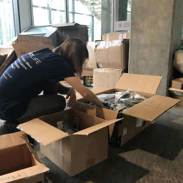 person hunched over moving boxes, packing them