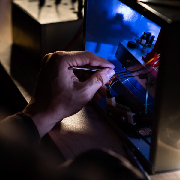 A person's hand is seen holding an instrument near wires.