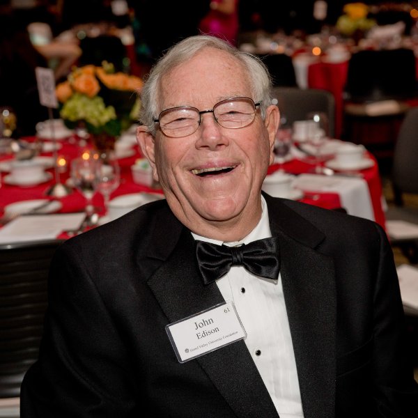 photo of man in tuxedo and black tie seated at table