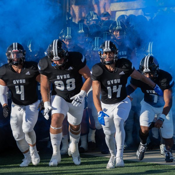 Football players run through smoke at start of game