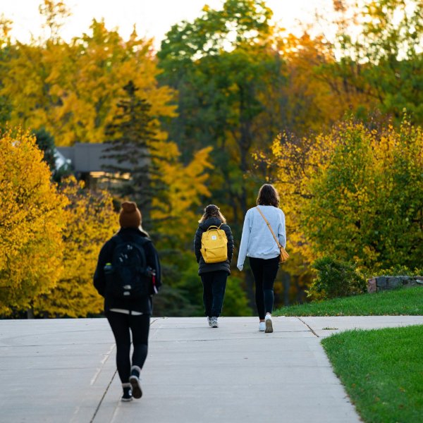 three people walking on Allendale Campus, their backs to the camera