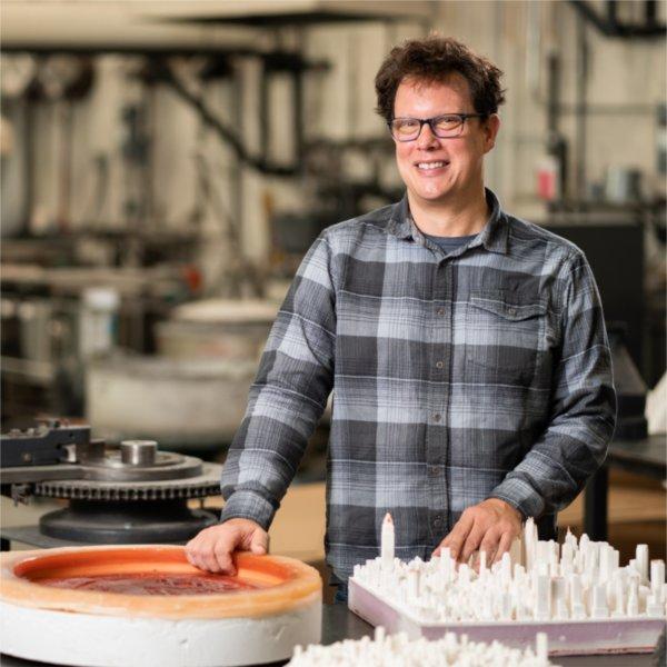 Visual and media arts faculty member Norwood Viviano poses in his studio with some of his 3D printed creations.
