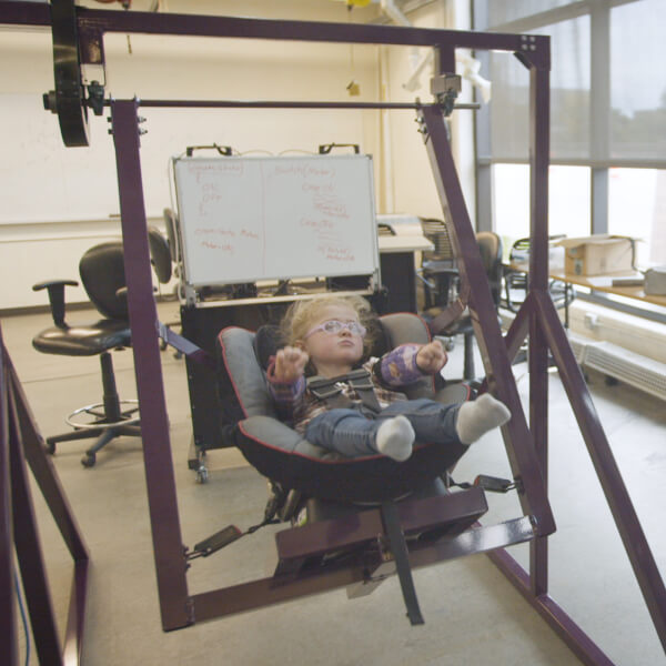 Sarah Truax, right, smiles as her daughter, Alexis, rides in a custom-built swing made by Grand Valley engineering students.