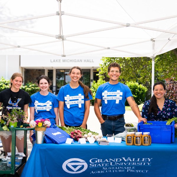 A group of people standing behind a table with produce for sale