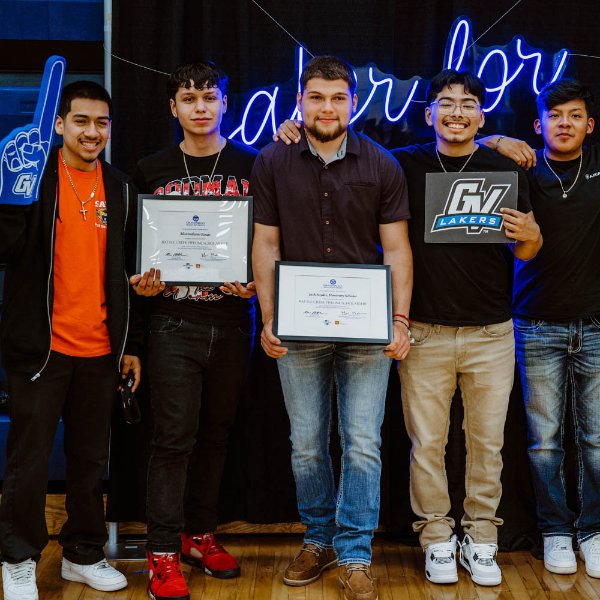 five students stand in front of neon Laker for a Lifetime, holding certificates or other props