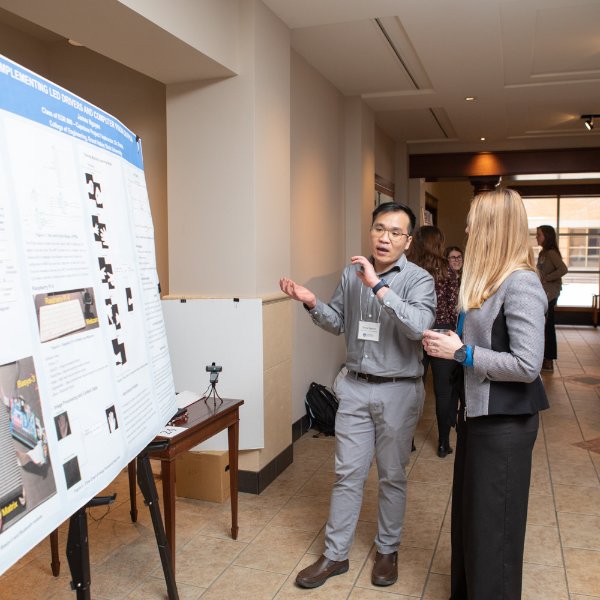 A graduate student presents their poster at the Graduate Showcase.