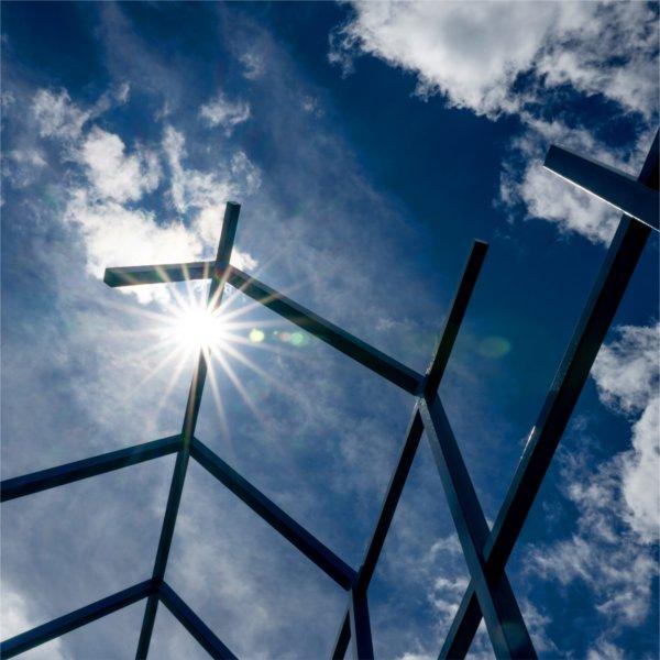 A blue metal sculpture is seen with a backdrop of a blue sky.