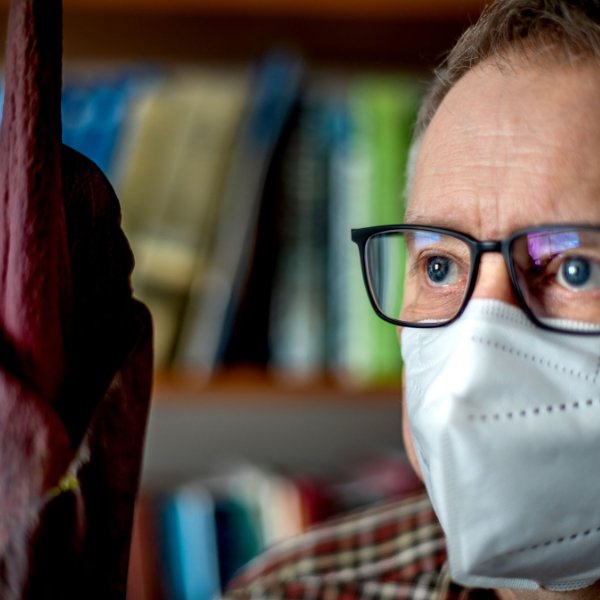 Todd Carlson, wearing a mask, looks at the blooming voodoo lily.