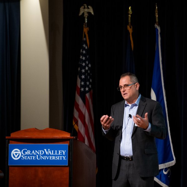 David Leich, executive director of global supply chain for General Motors, speaks next to a podium and in front of several flags on a stage.