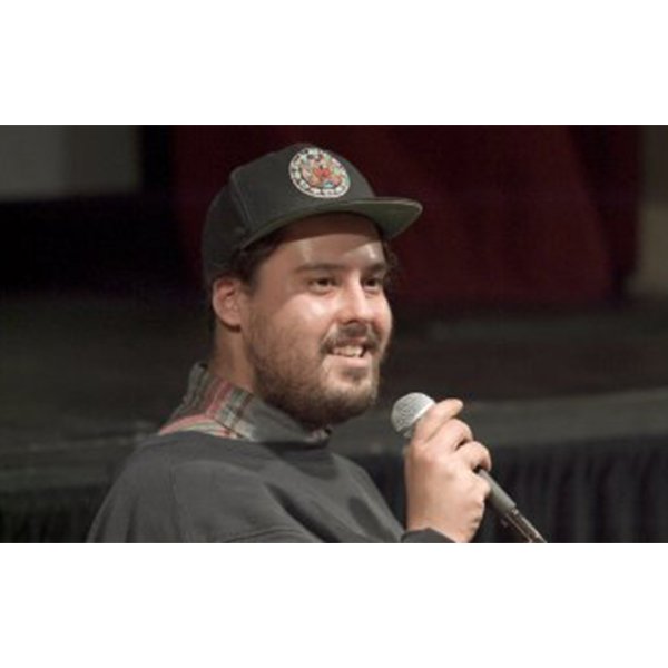 A person grins while holding a microphone.