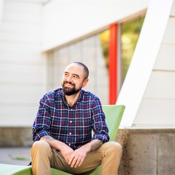 Sean Carney looks off to the side while sitting outside a building.