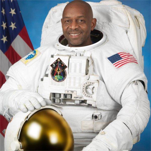 A person in an astronaut uniform smiles for the camera.