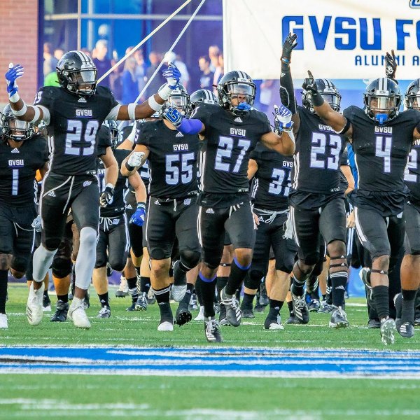 GVSU football team in black uniforms run onto the field at Lubbers Stadium