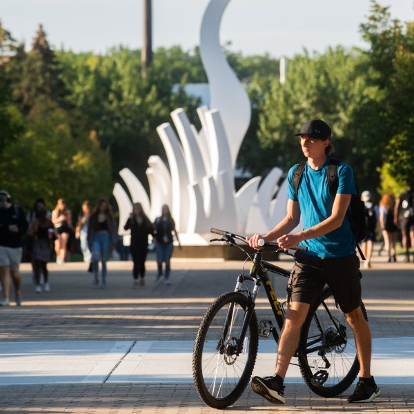 Student walking his bike on campus.