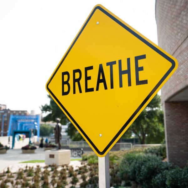 A yellow sign with the word "breathe" is shown outside a building.
