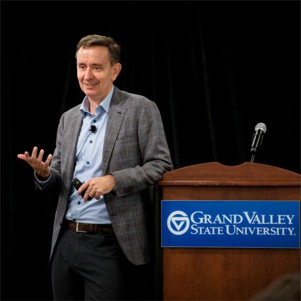 Peter Felten stands by podium, in suit jacket and blue shirt, no tie