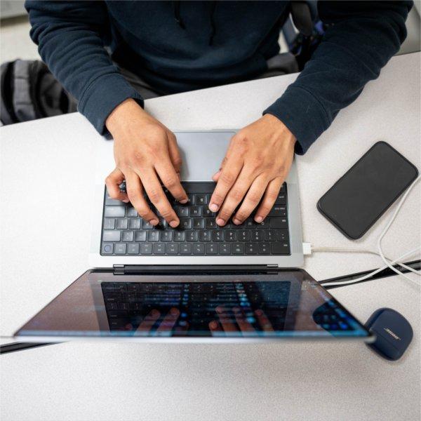 Overhead view of a person typing on a laptop at a desk.